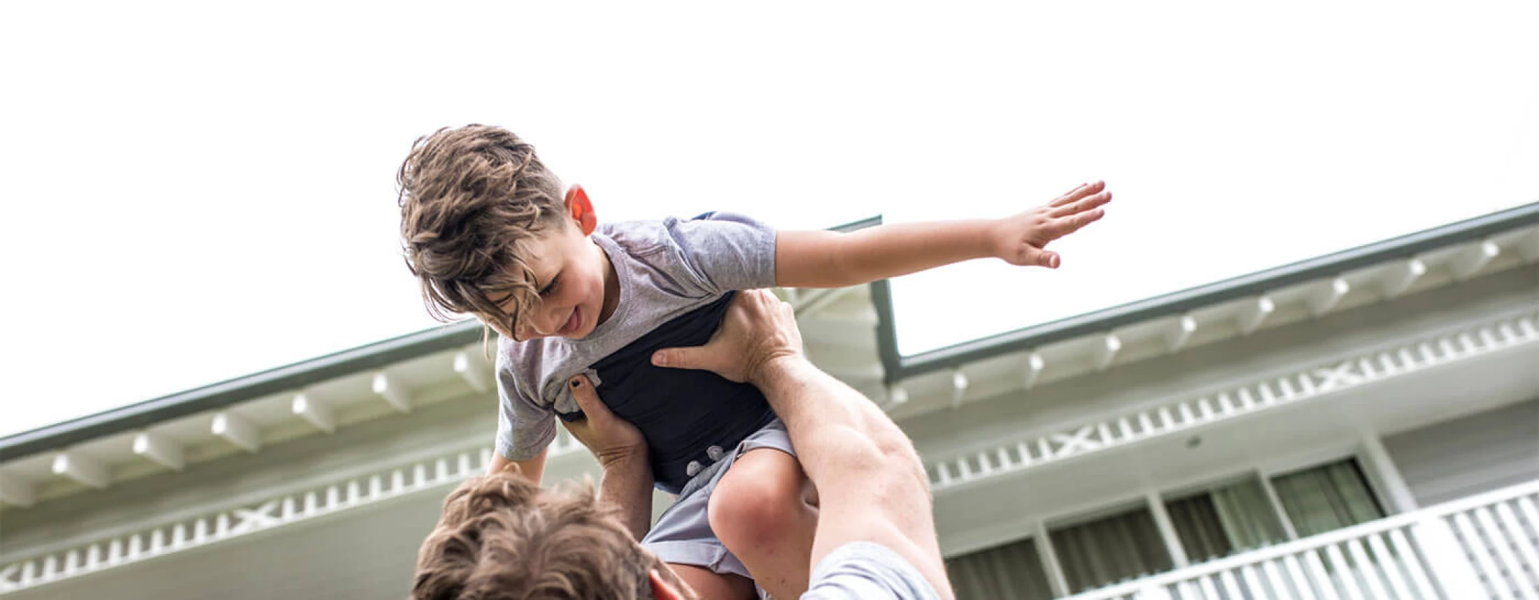 adult-holding-child-up-in-front-of-house